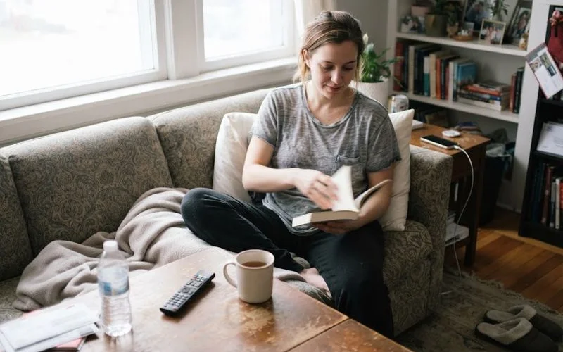 A patient in a supportive post-surgical garment resting at home during the first week of breast augmentation recovery, calm and comfortable setting